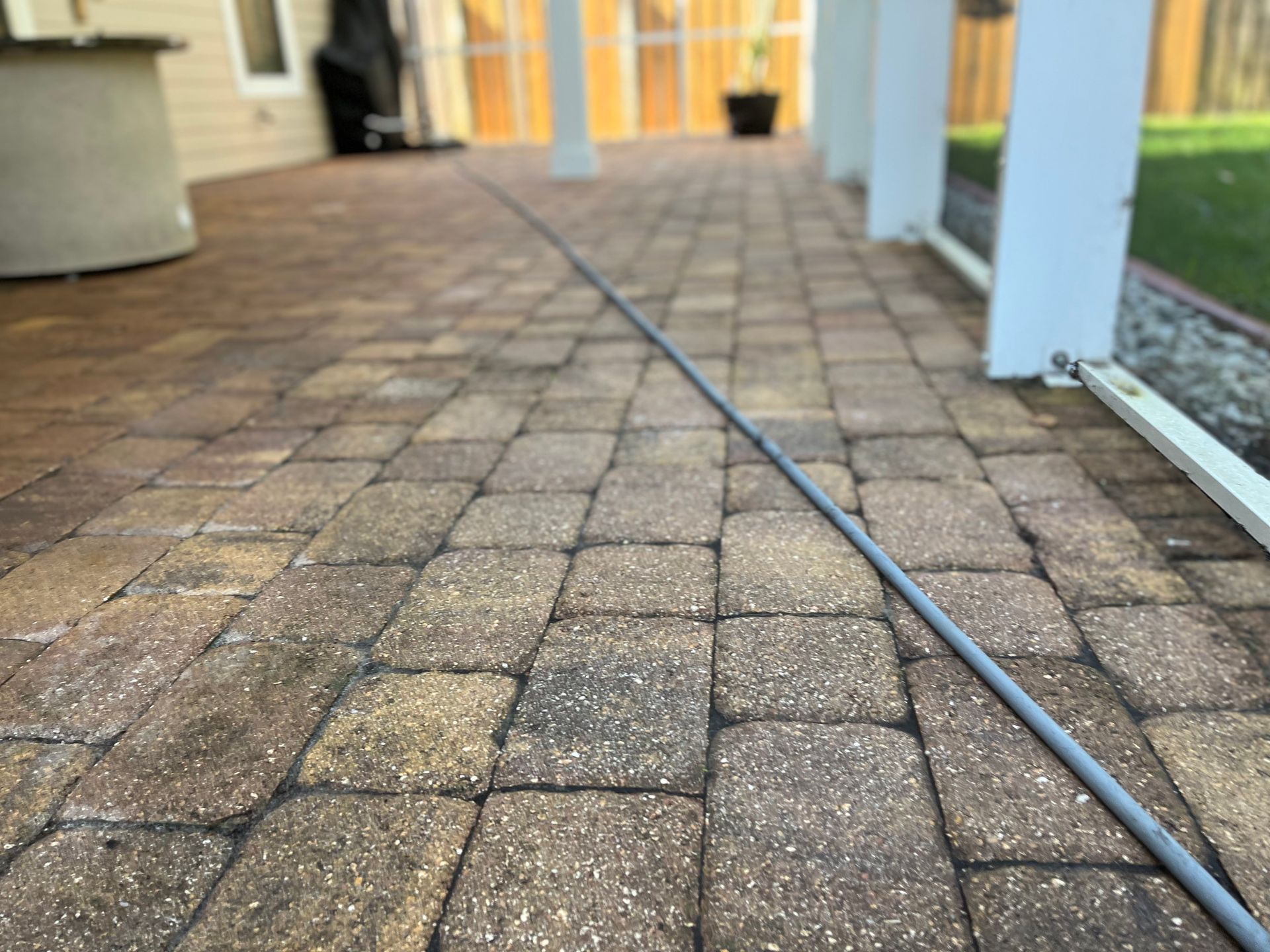 A hose is laying on a brick walkway.