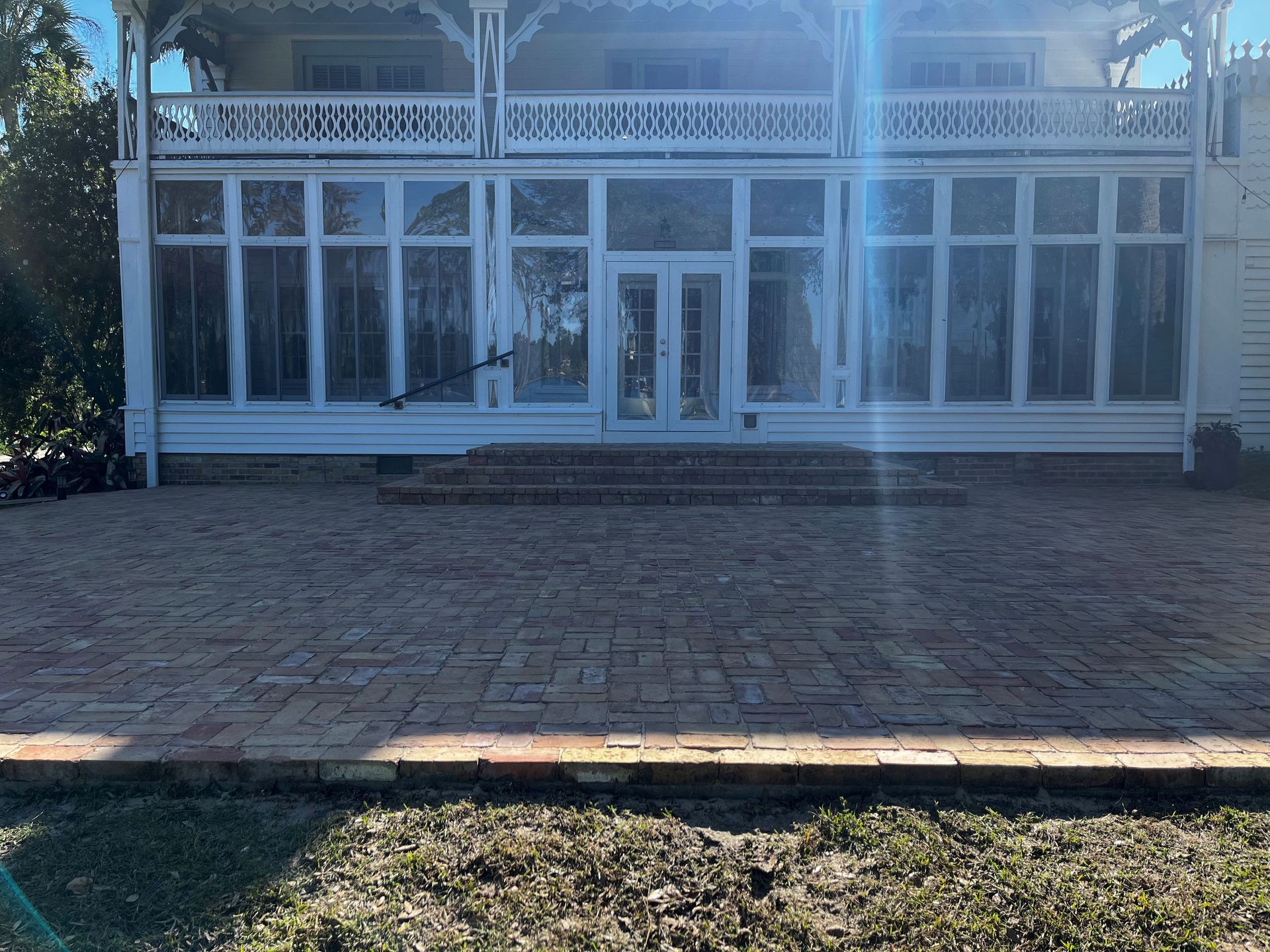 A large white house with a brick patio in front of it.