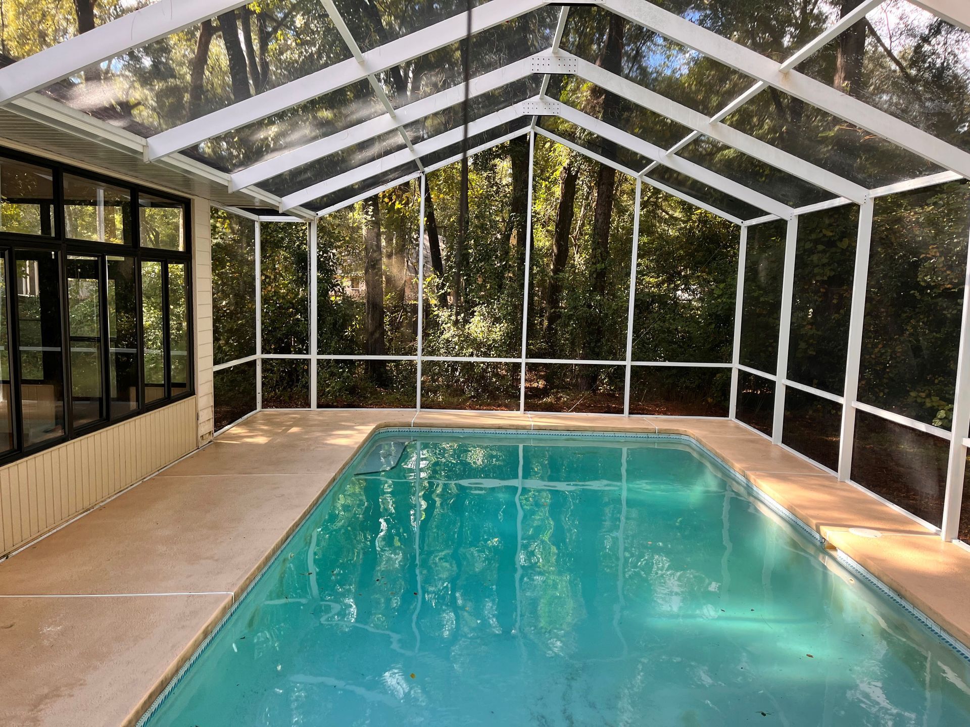 An indoor swimming pool with a screened in area and a clear roof.