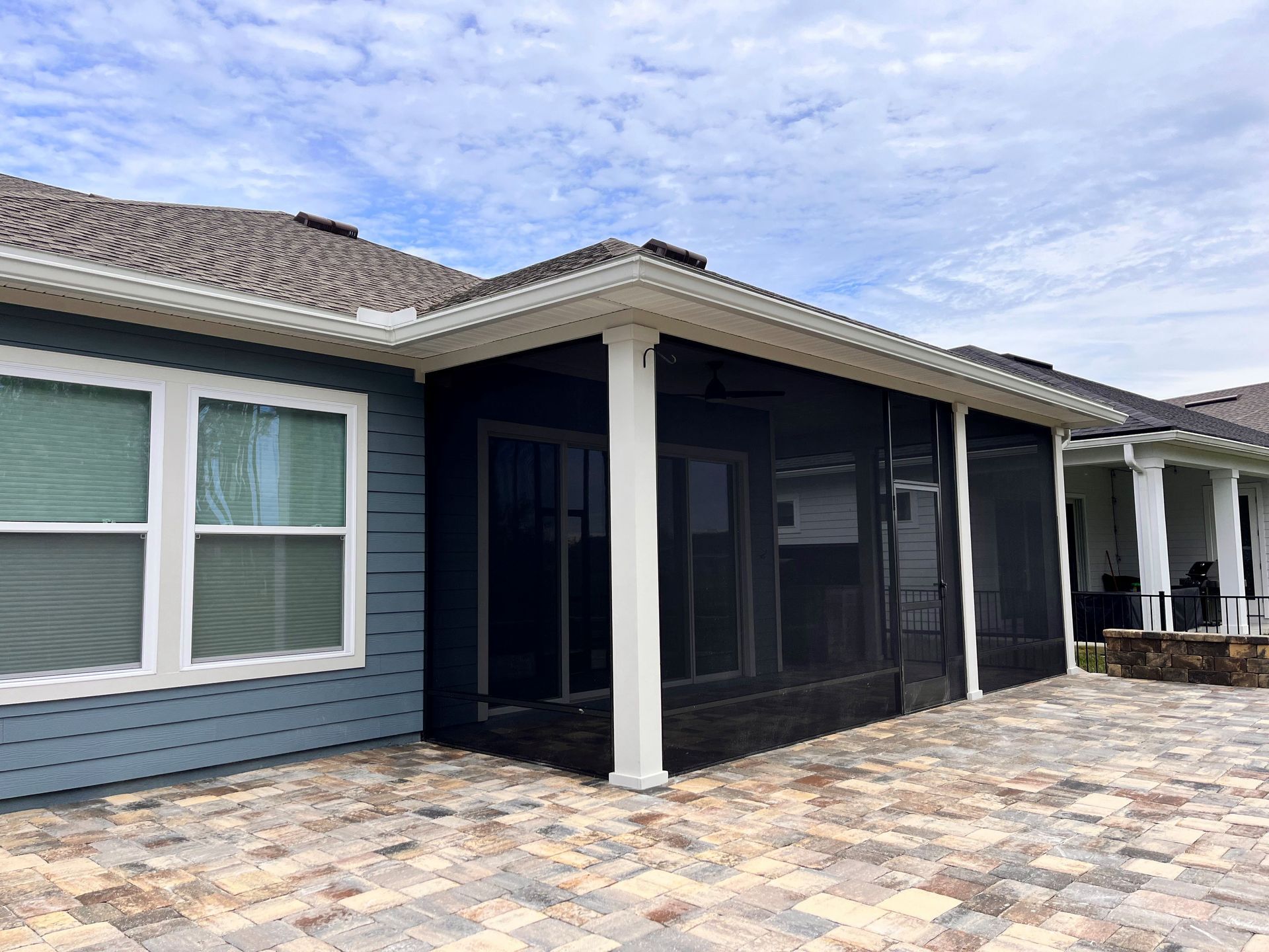 The back of a house with a screened in porch and patio.