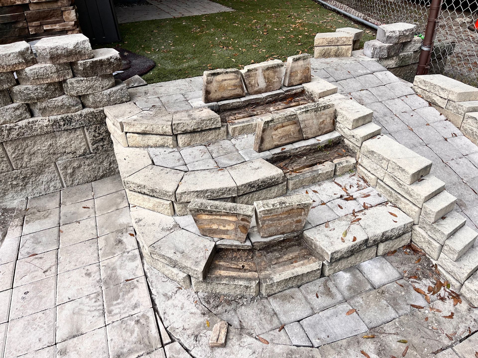 A brick fire pit is being built on a patio.