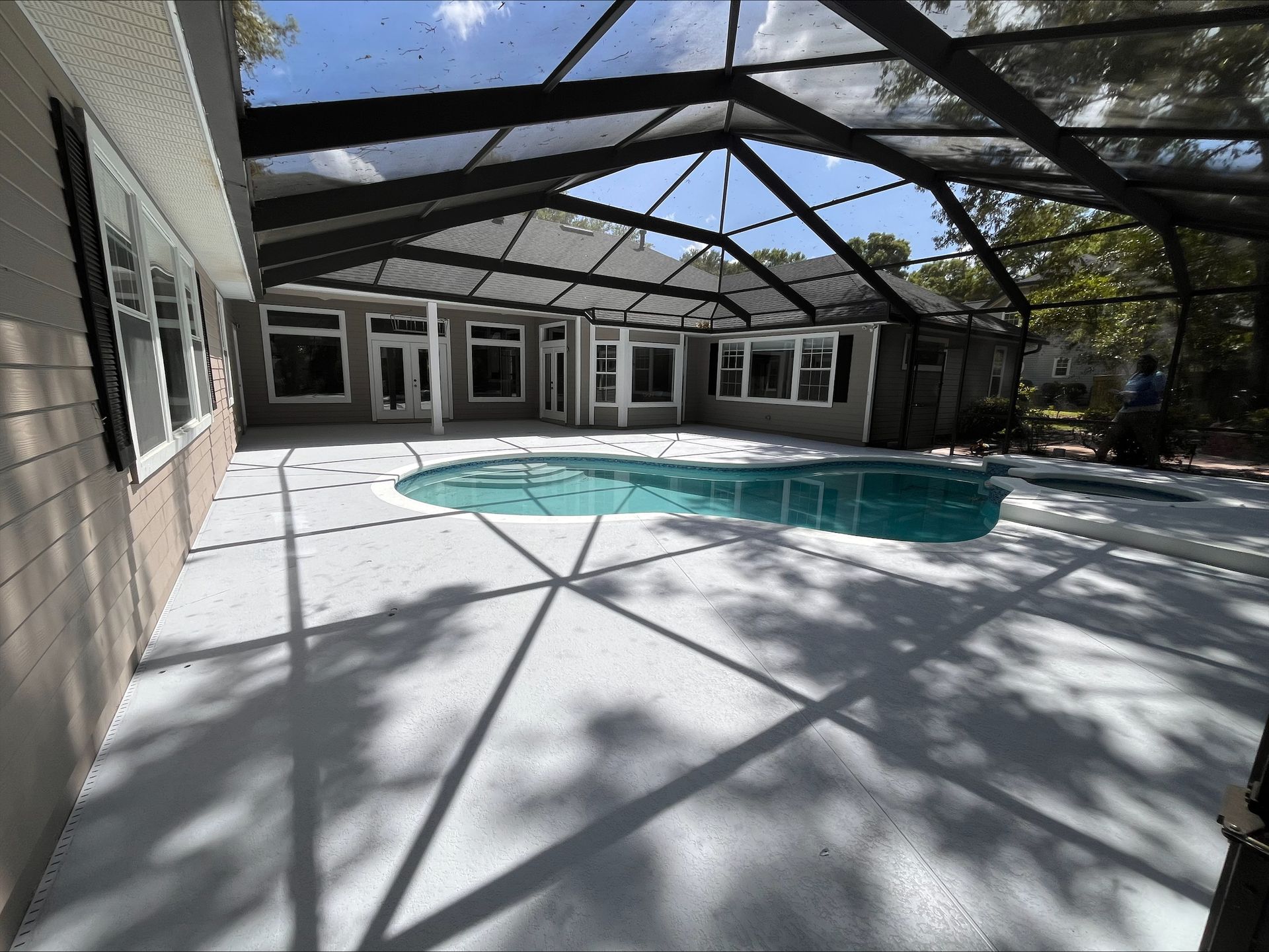 The back of a house with a screened in porch and patio.