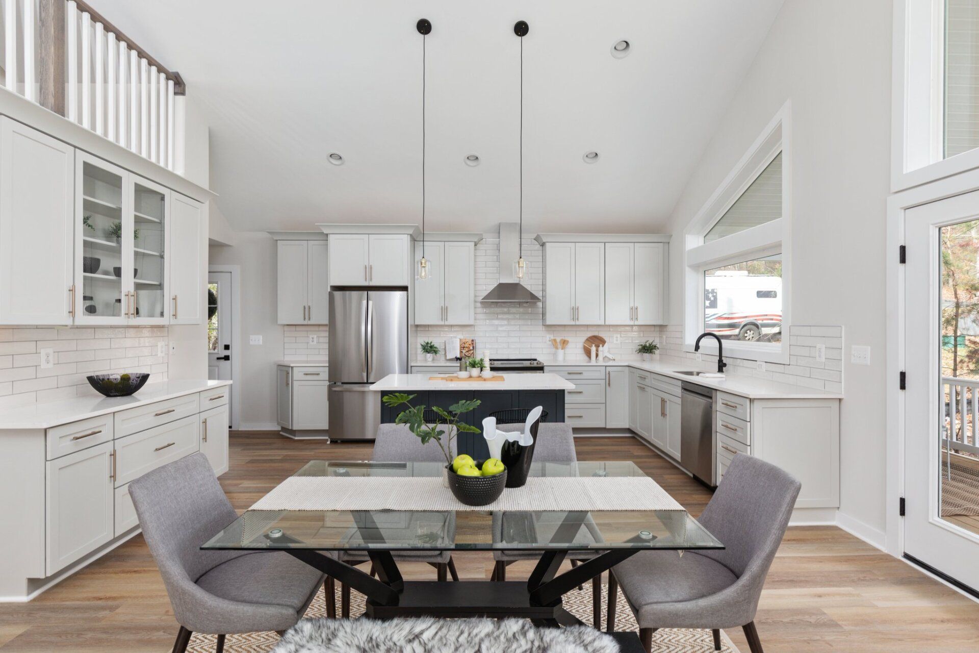 A kitchen and dining room in a house with a glass table and chairs.