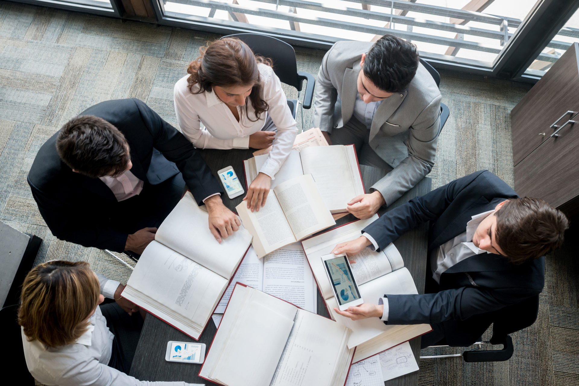 A group of people are sitting around a table with books.