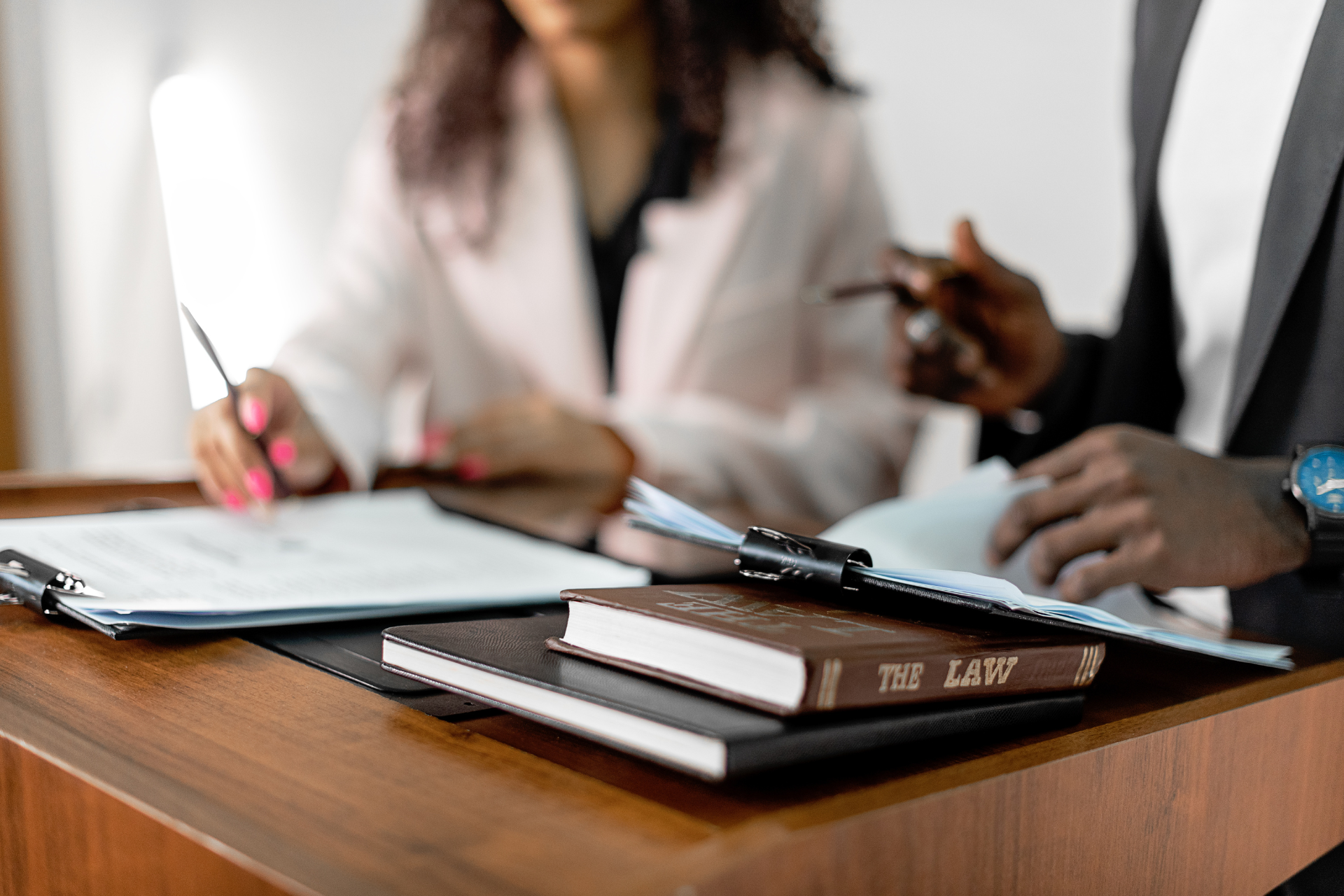 A man and a woman are sitting at a desk with papers and books.