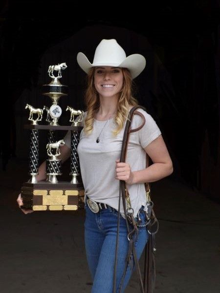 A woman in a cowboy hat is holding a trophy