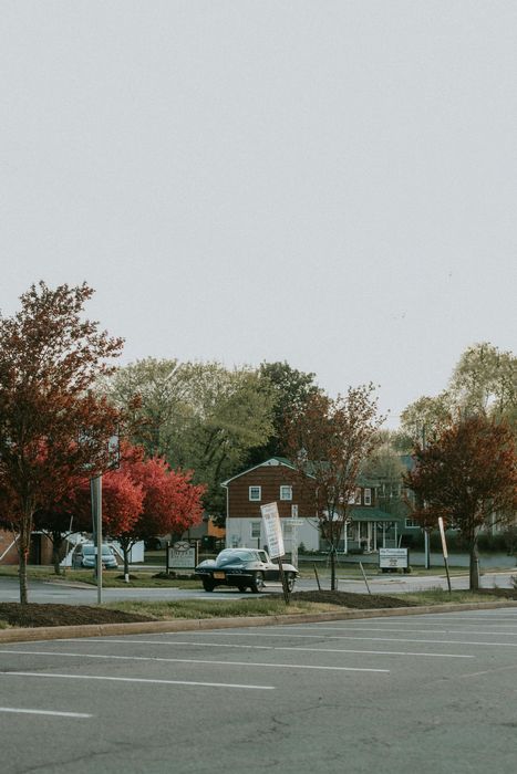 A car is driving down a street in front of a house