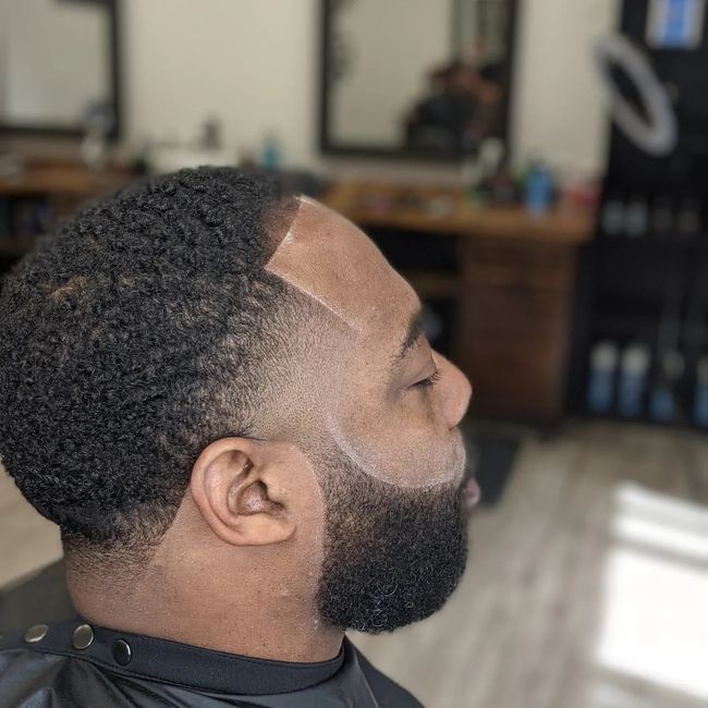 A man with a beard is getting his hair cut at a barber shop