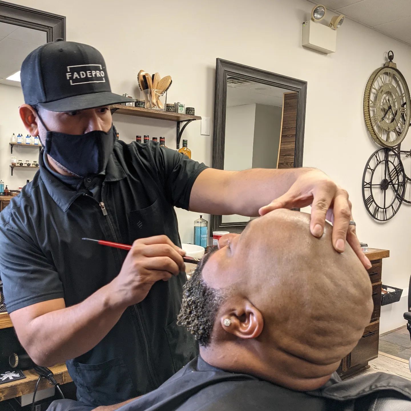 A man is getting his hair cut by a barber wearing a mask.