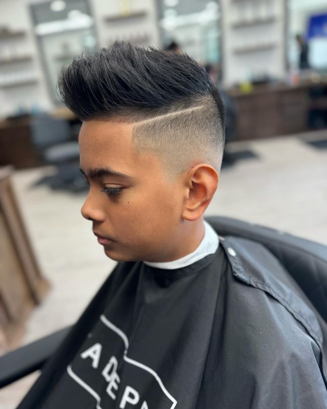 A young boy is getting his hair cut at a barber shop.