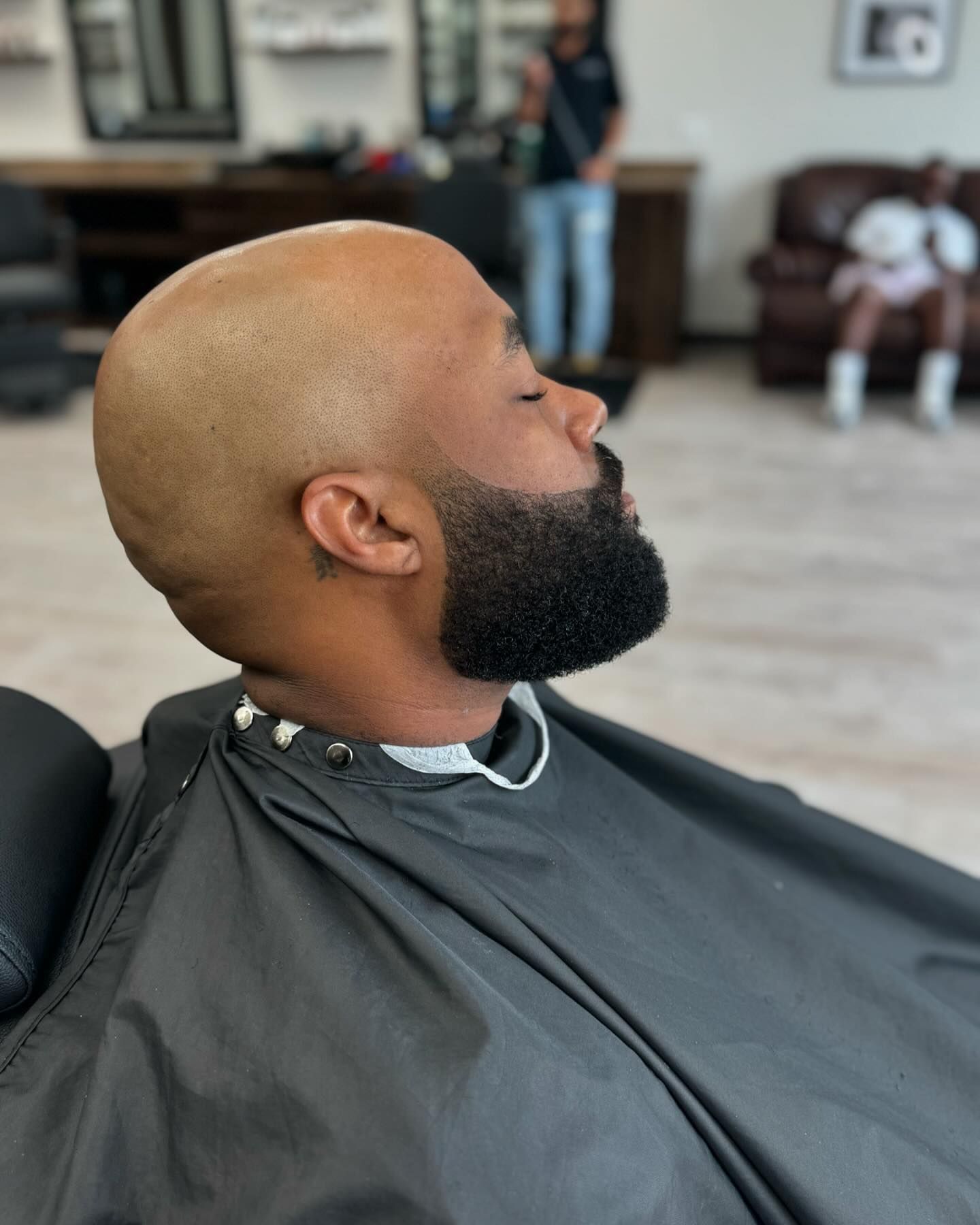 A man with a beard is getting his hair cut at a barber shop