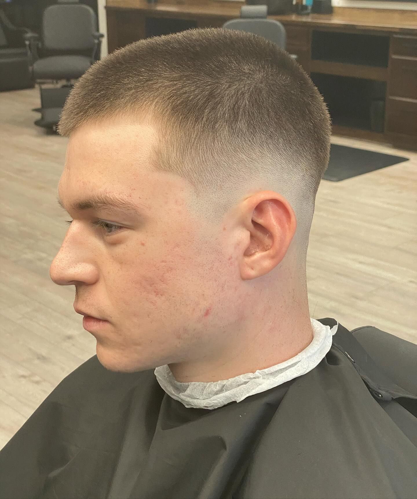 A young man is getting his hair cut at a barber shop.