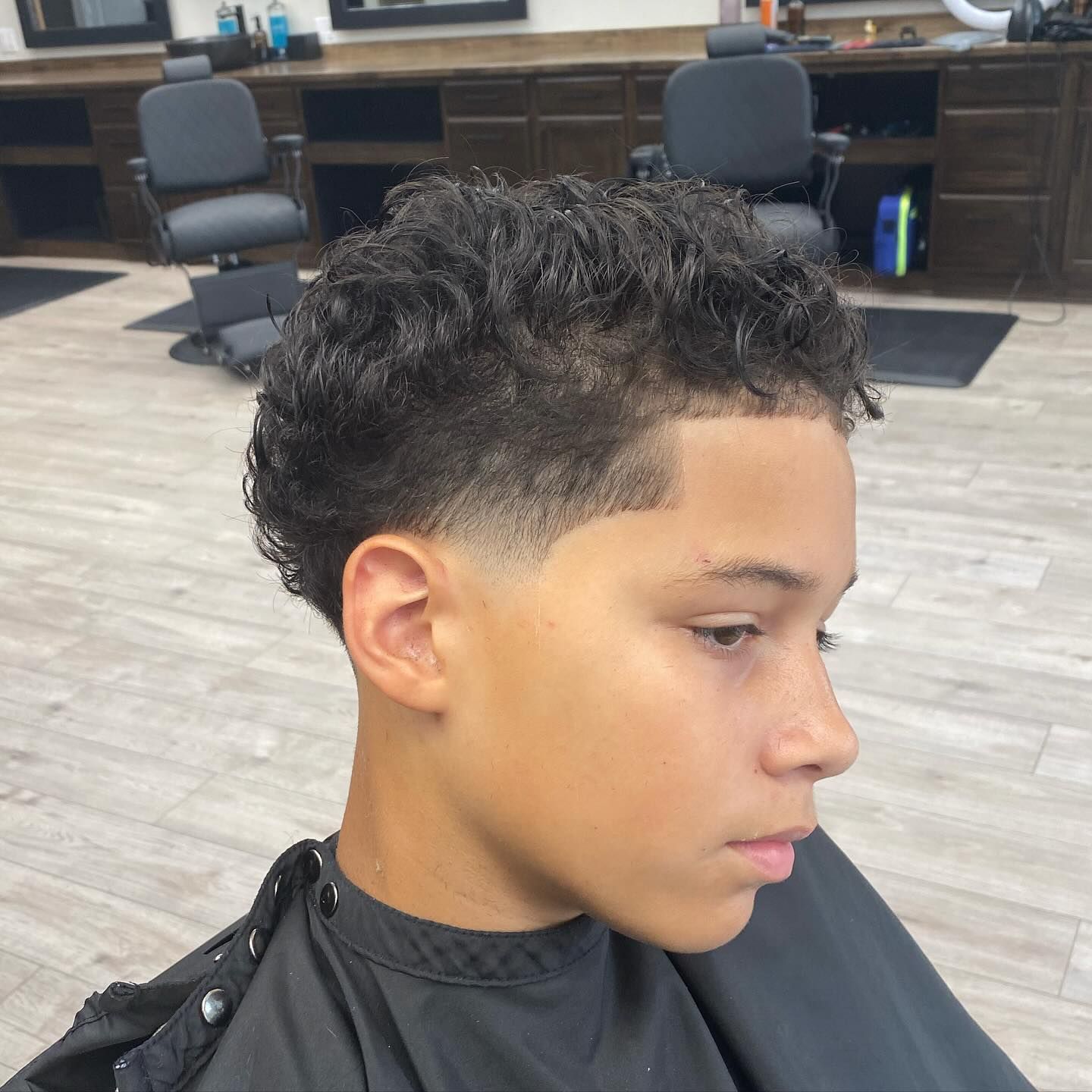 A young boy is getting his hair cut at a barber shop