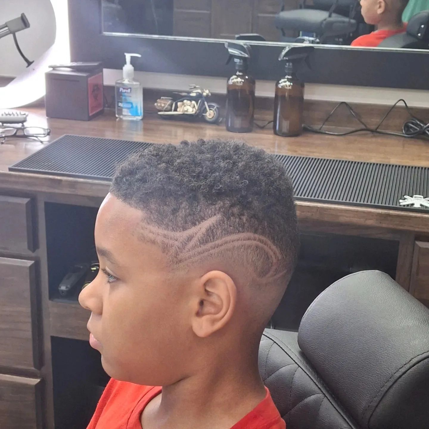 A young boy is getting his hair cut at a barber shop