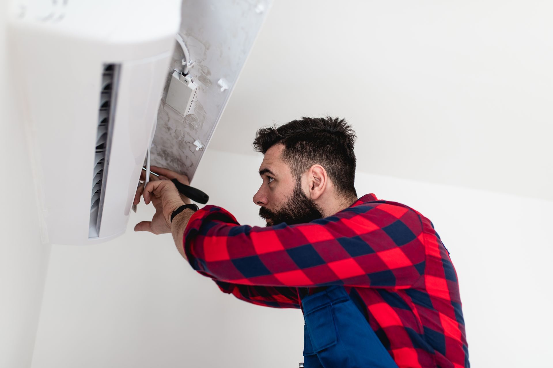 A man is fixing an air conditioner on the wall.