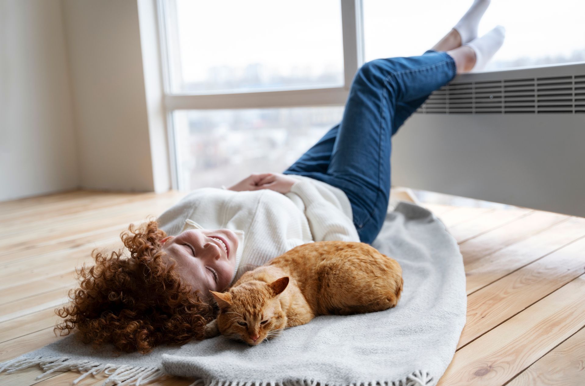 A woman is laying on the floor with a cat.