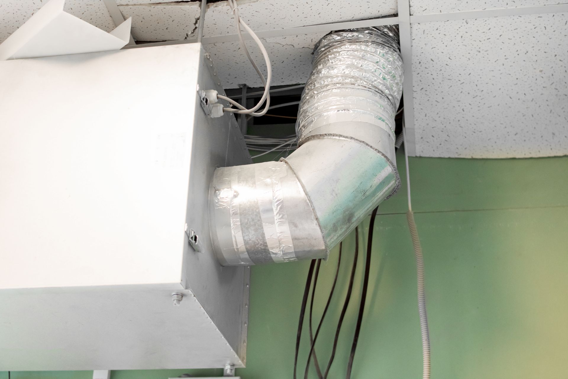 A white box with a hose attached to it is hanging from the ceiling.