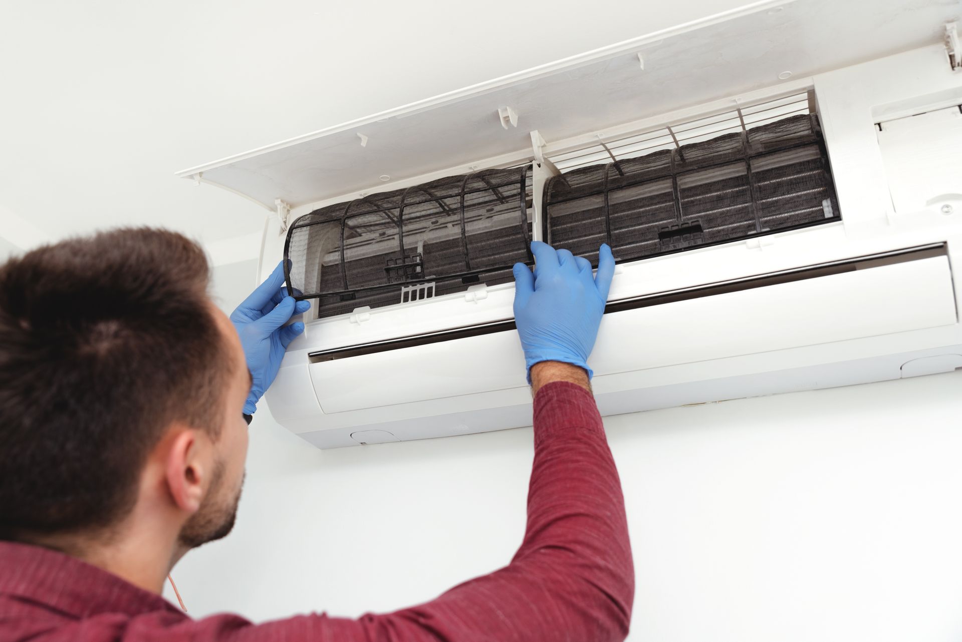 A man is cleaning an air conditioner with a magnifying glass.