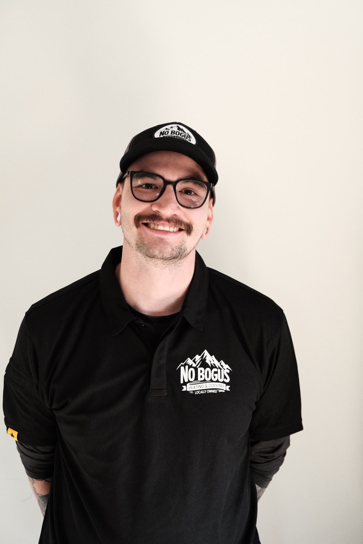 A man wearing a hat and glasses is smiling for the camera.