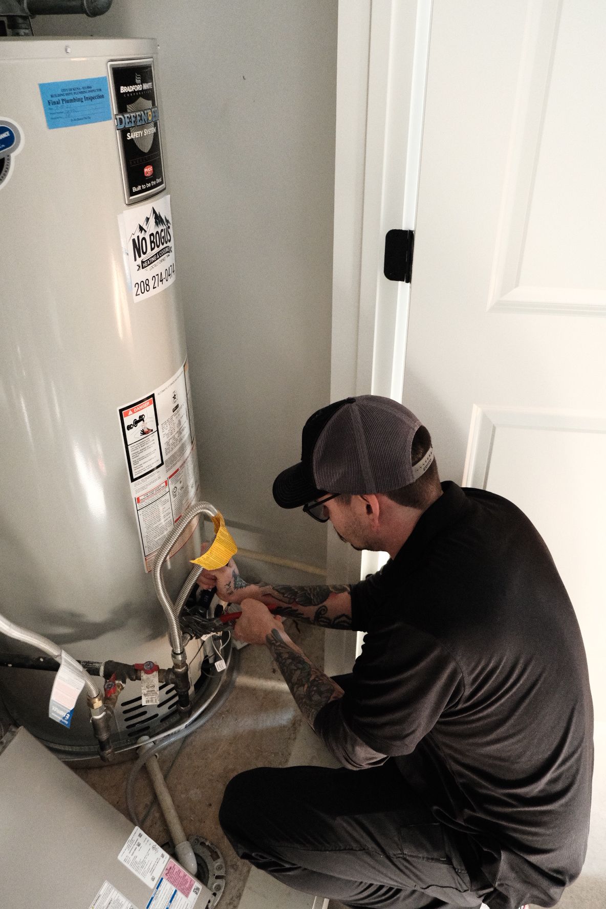 A man is fixing a water heater in a bathroom.