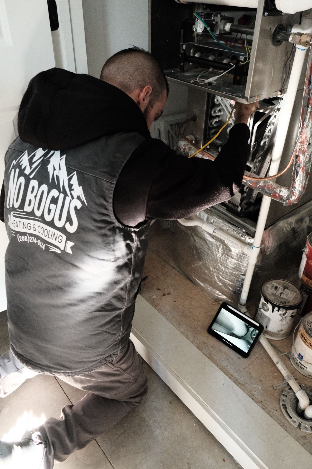 A man in a vest is working on a heating system.