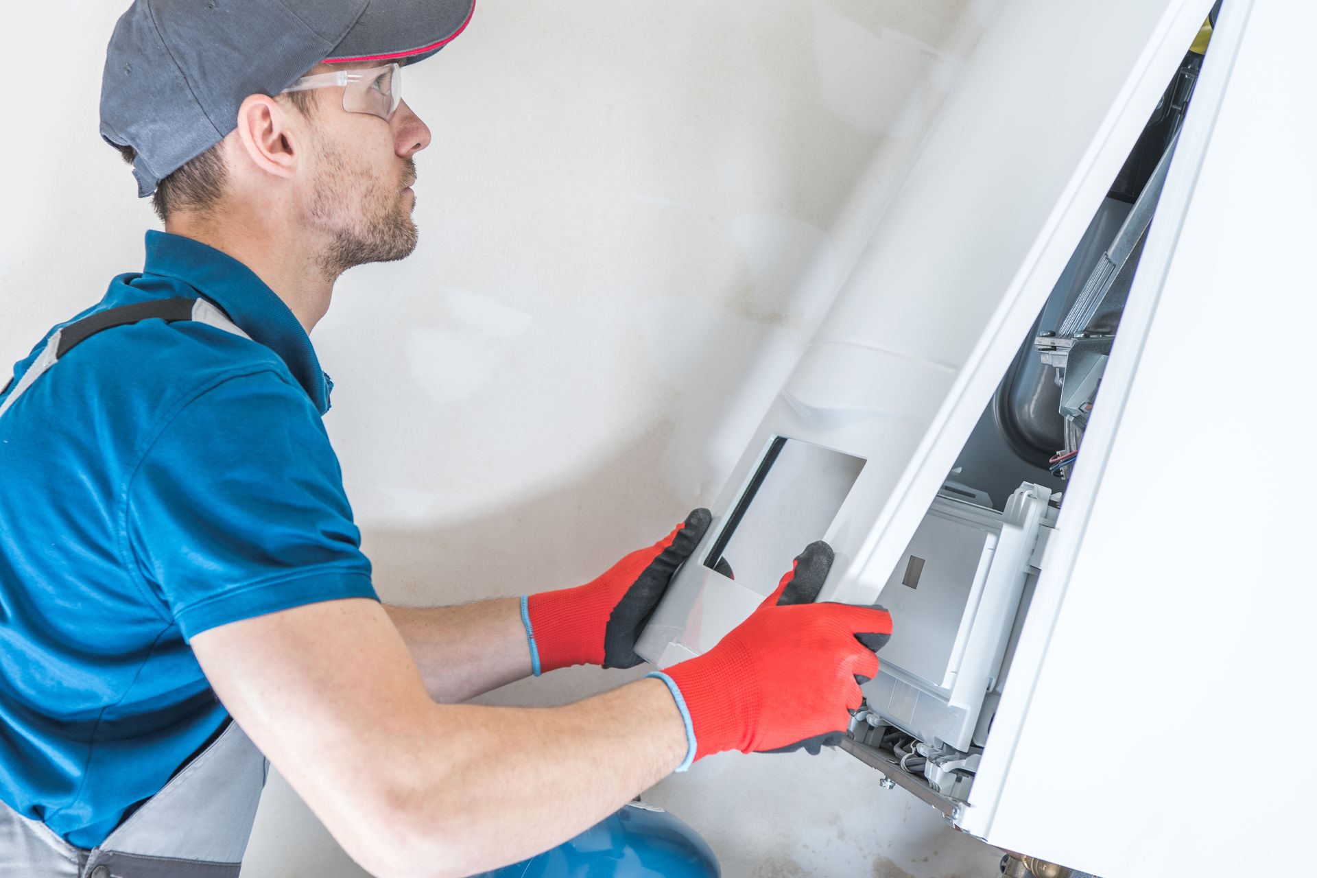 A man is working on a boiler in a bathroom.