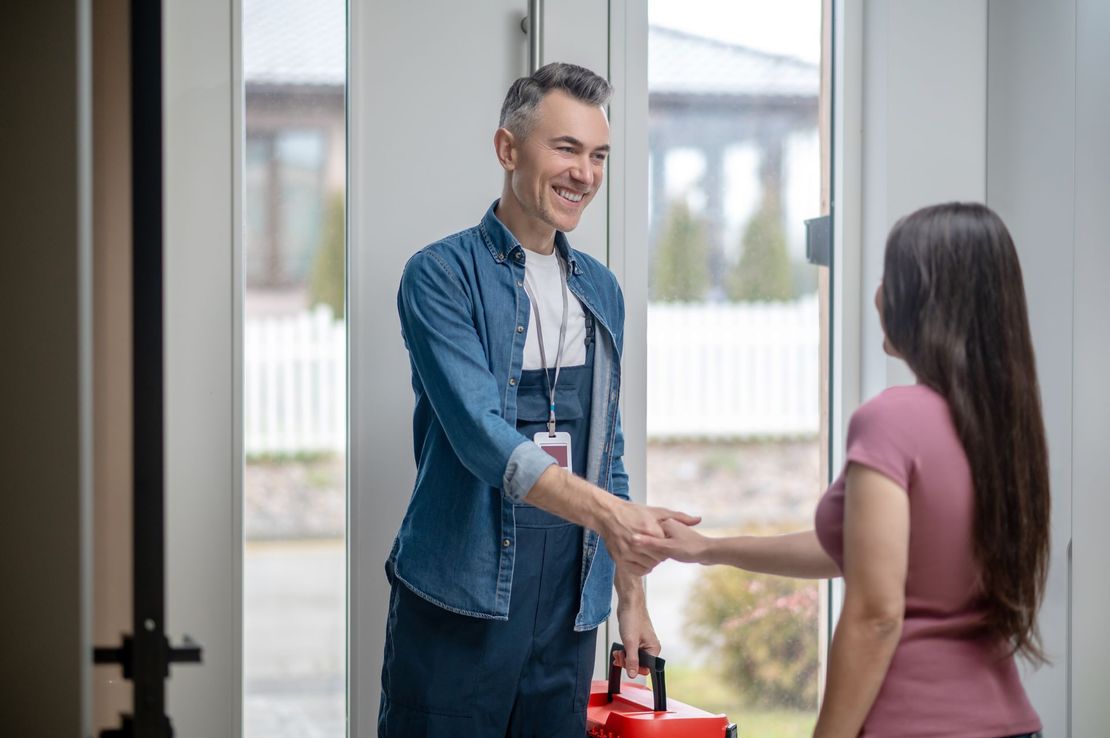 A man is shaking hands with a woman in a doorway.