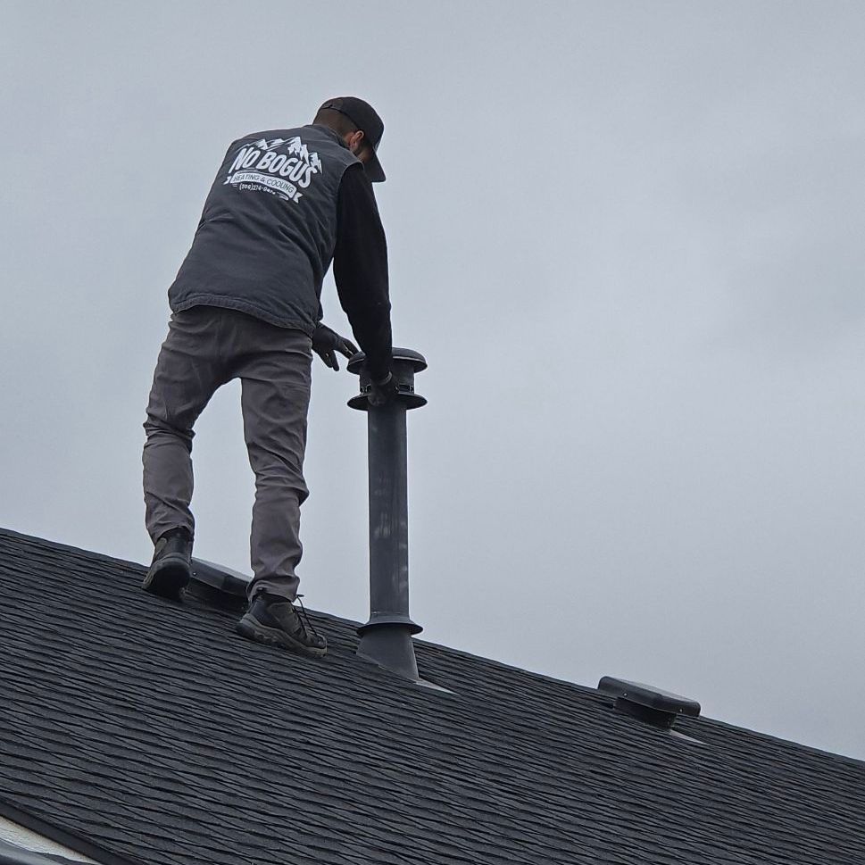A man is standing on top of a roof fixing a chimney.