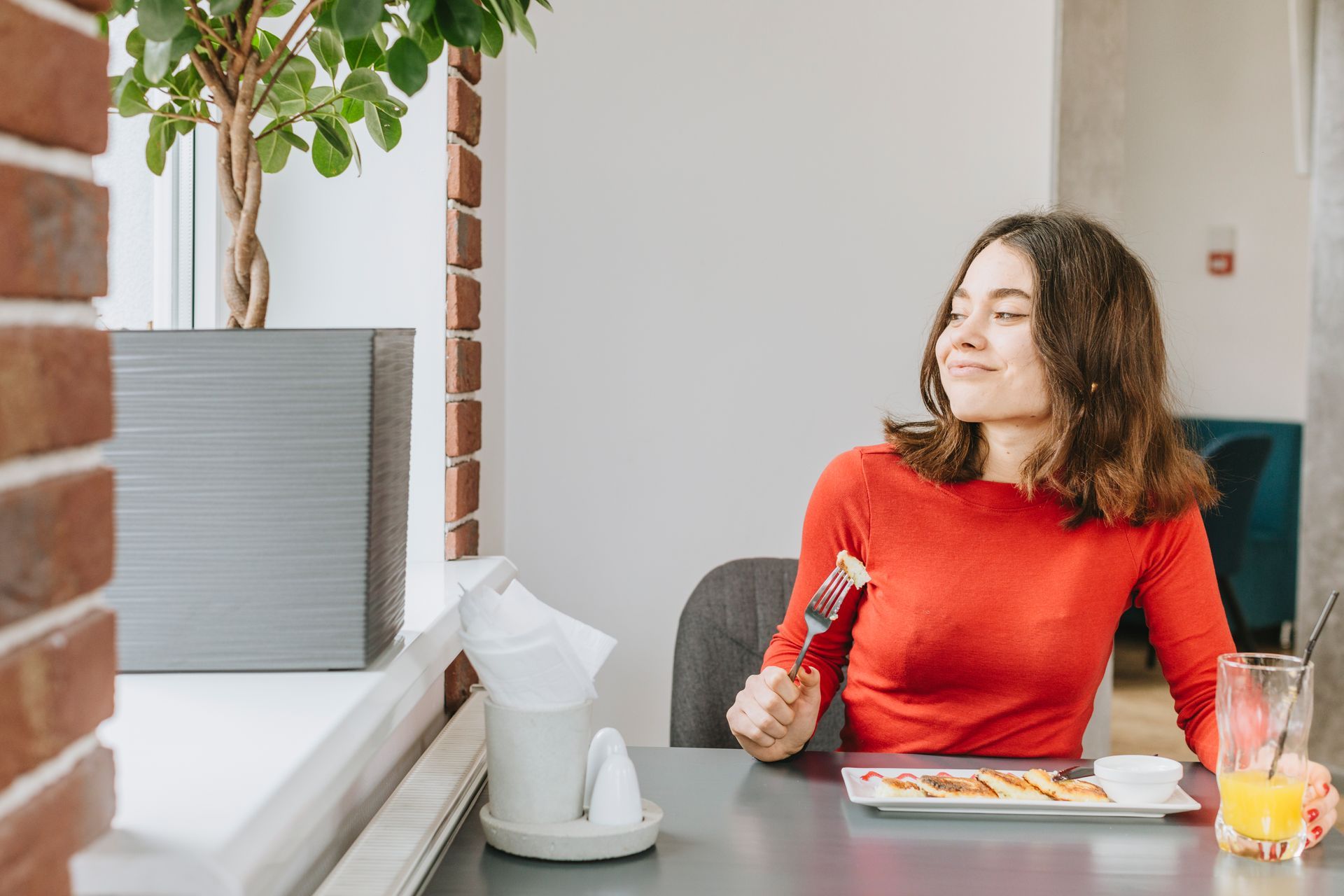 A woman is sitting at a table eating food with a fork.