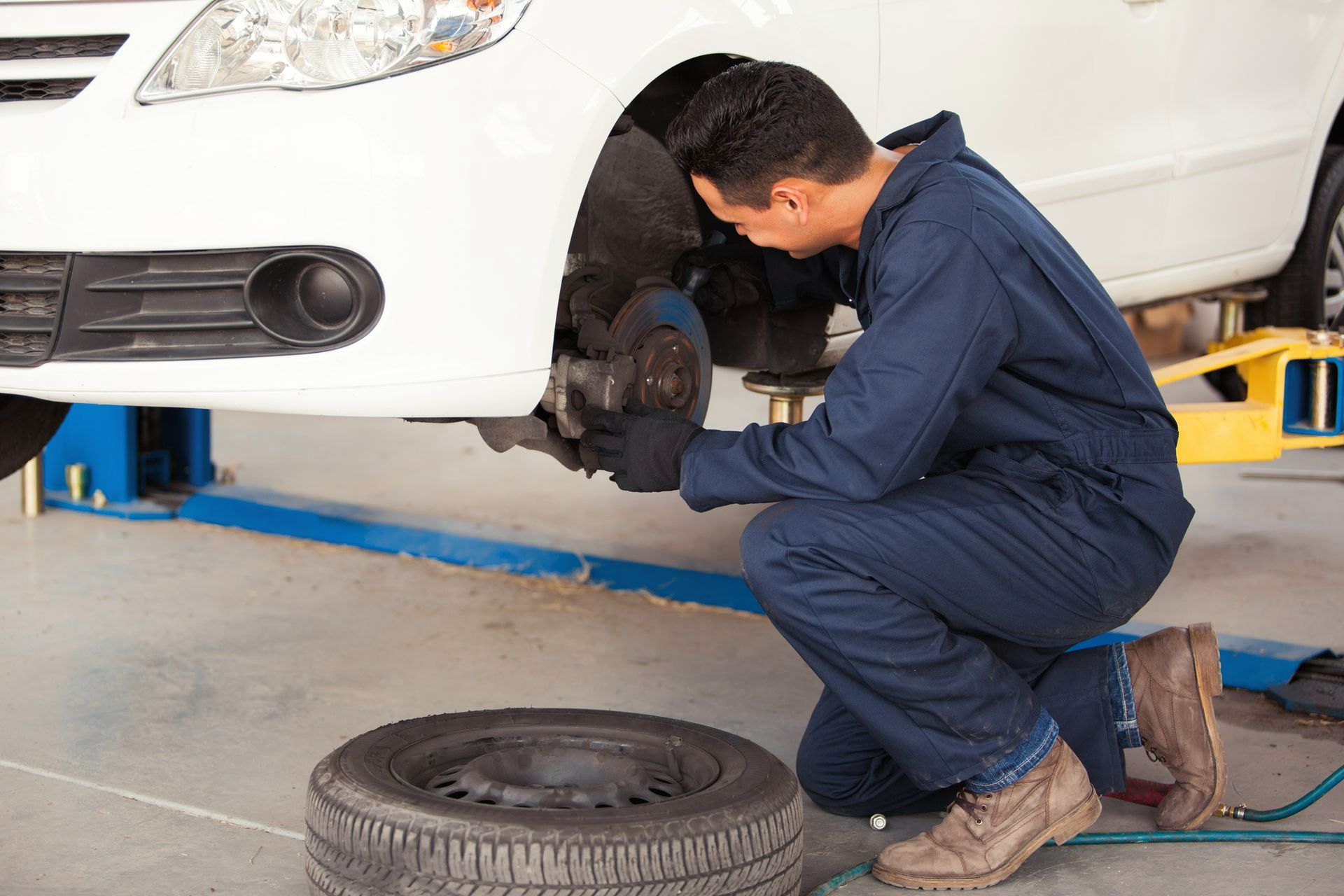 Mechanic checking car brakes in an auto repair shop – Pike, MD – Lynn's Automotive