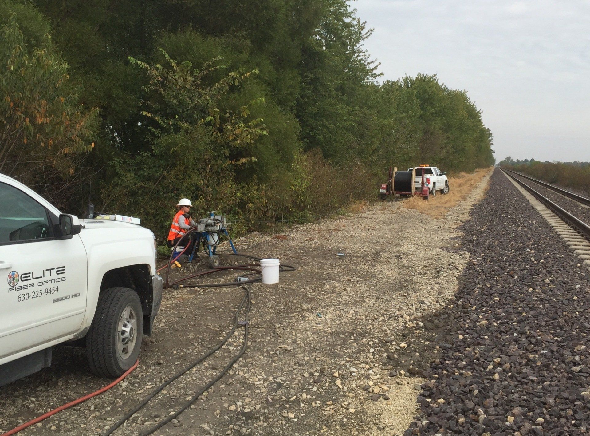 A white truck is parked next to a train track.