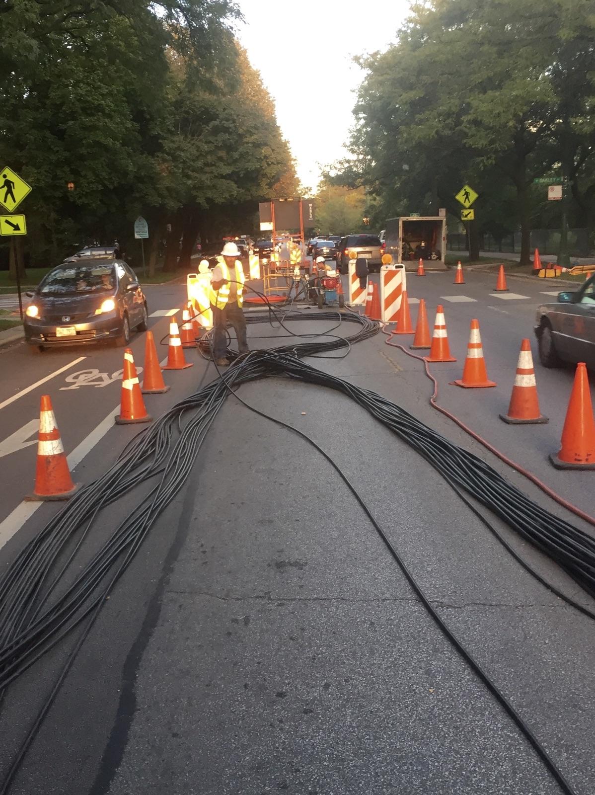 A bunch of orange cones are lined up on the side of a road