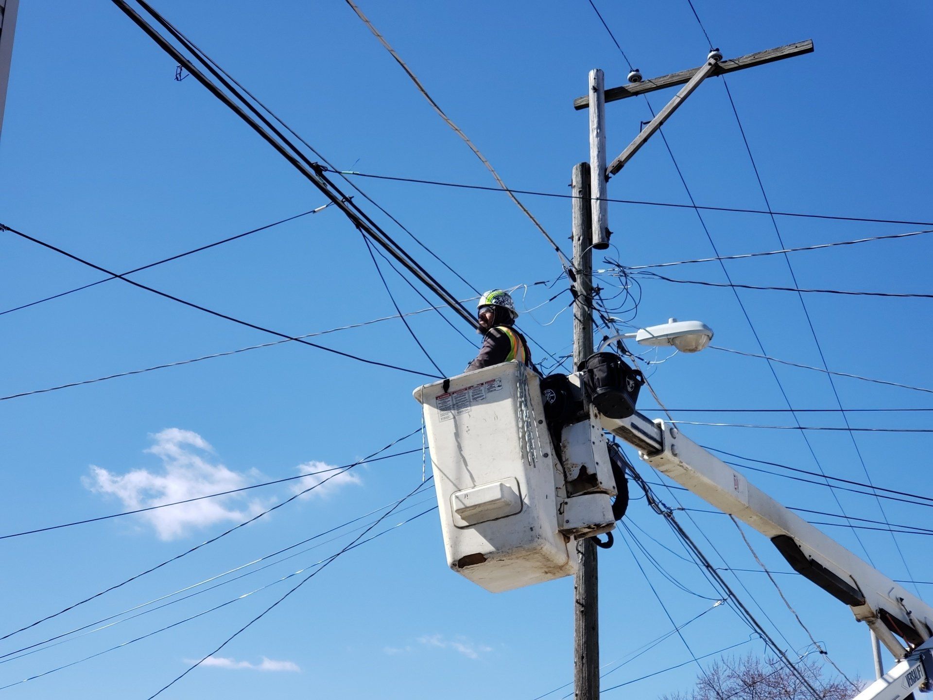 A man in a bucket is working on a power pole.
