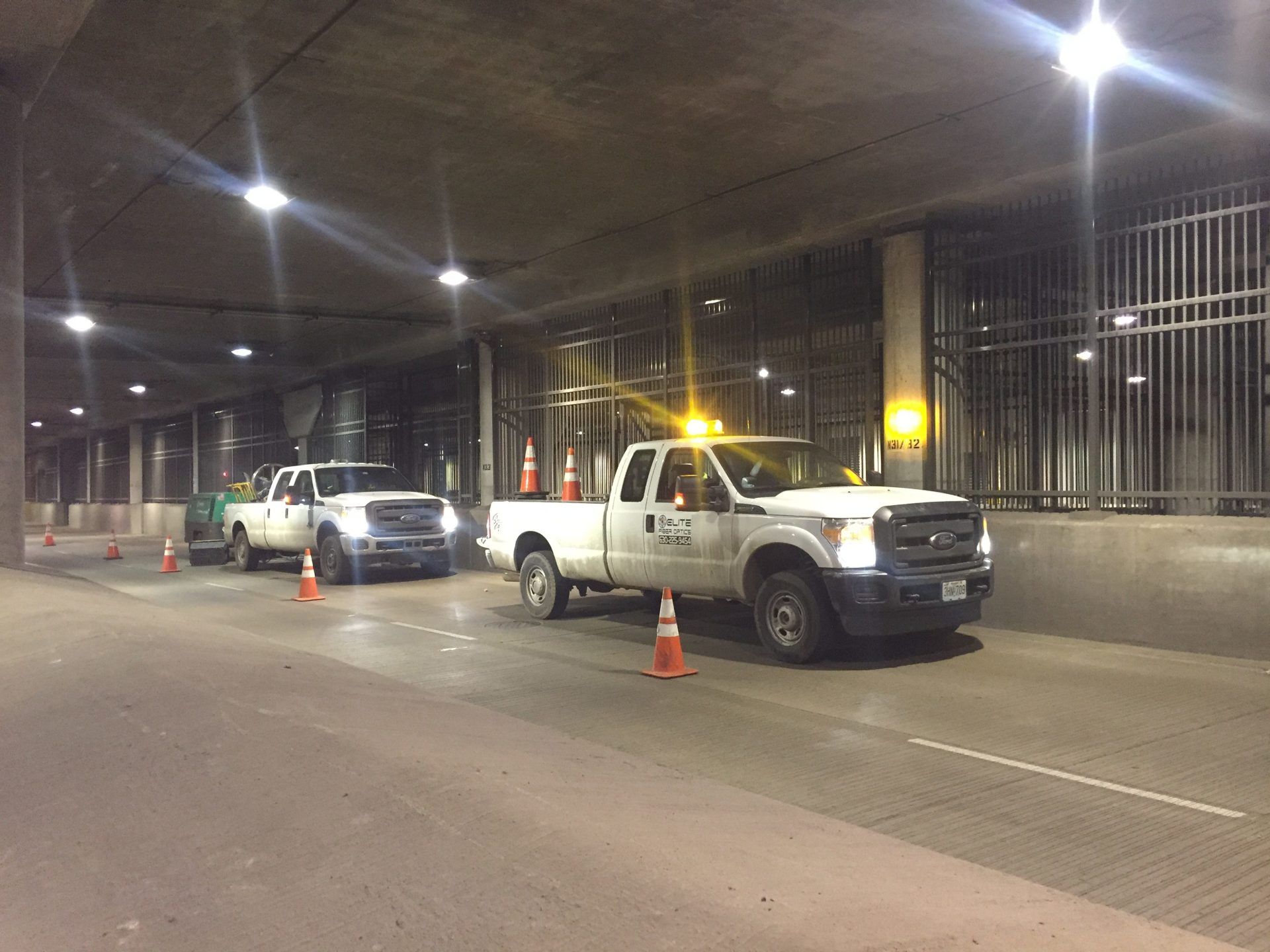 Two white trucks are parked next to each other in a parking garage.