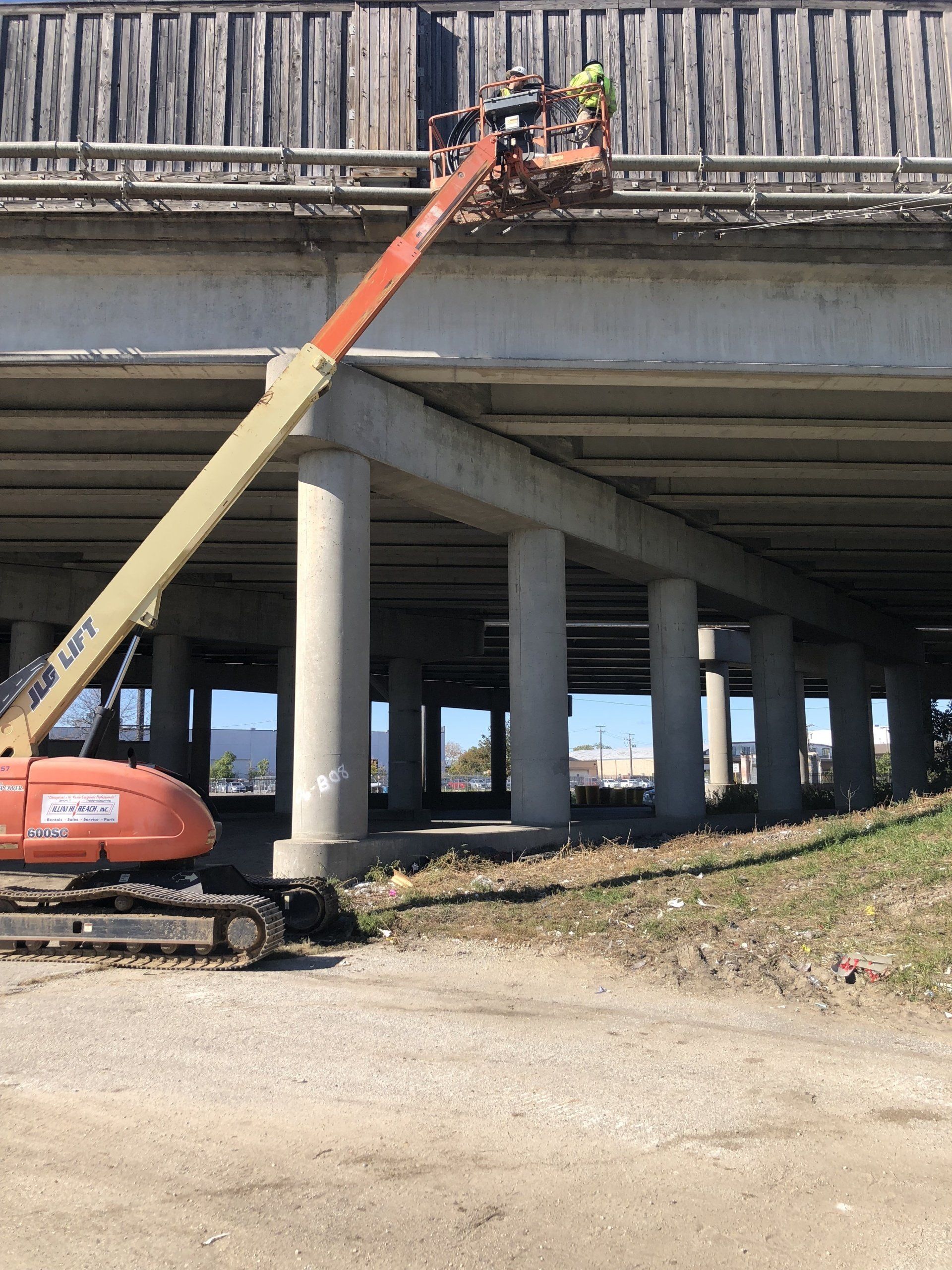 A jlg lift is being used to work on a bridge