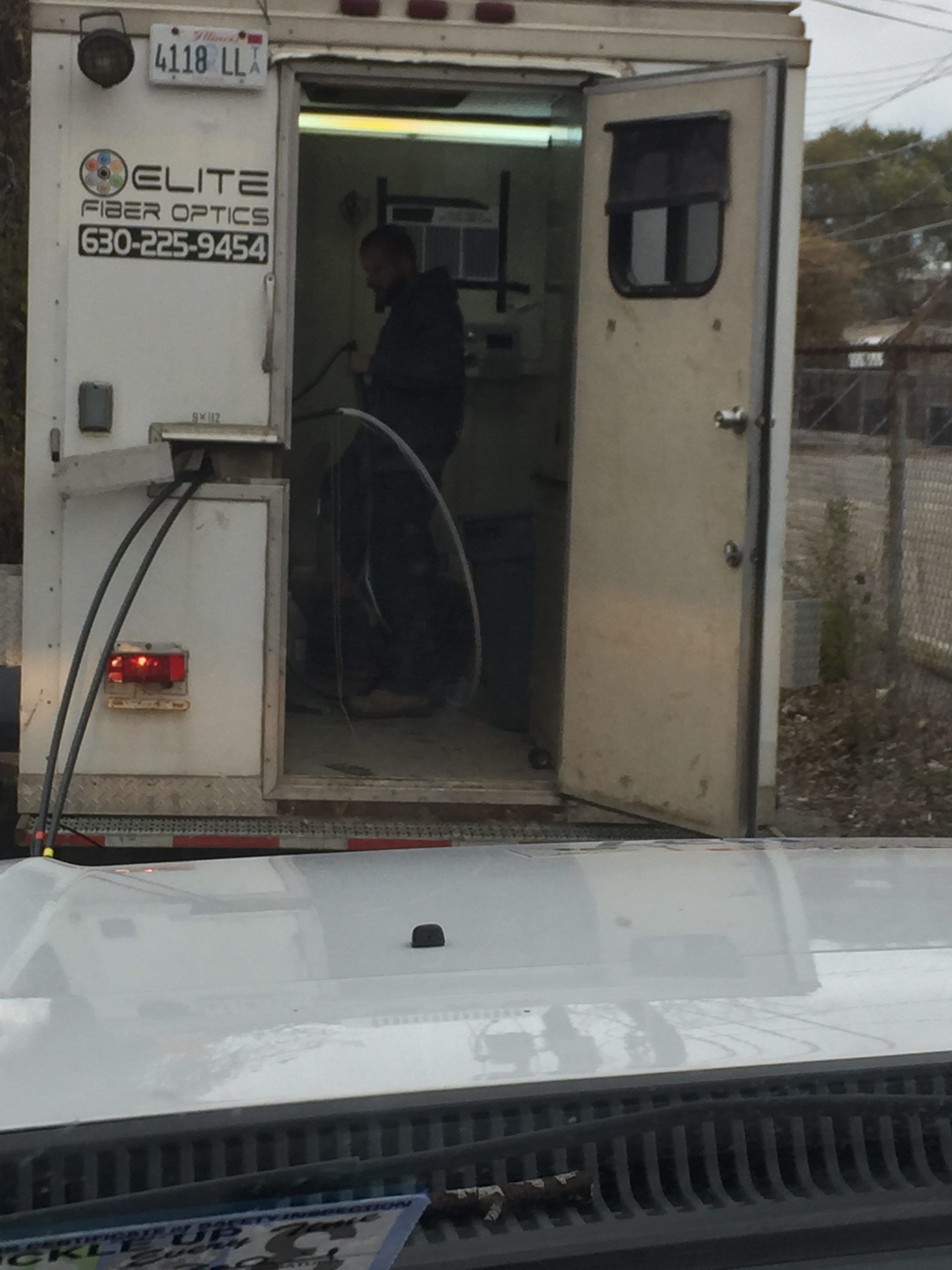 A man is working inside of a trailer that says elite fiber office