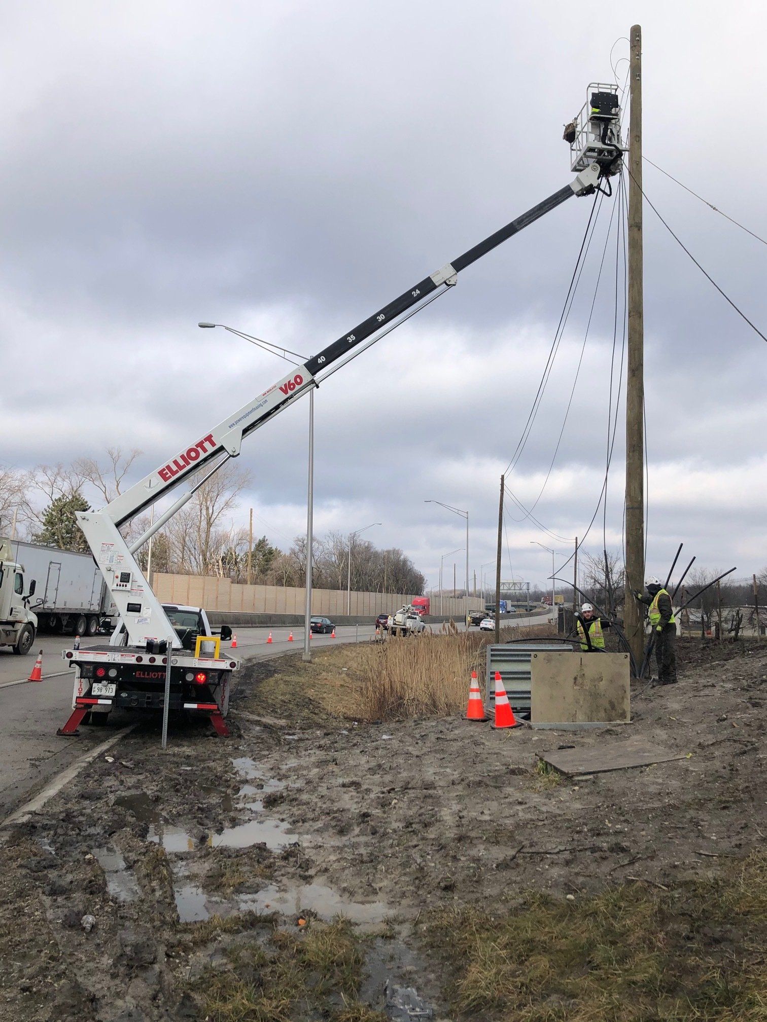 A truck with a crane attached to it is working on a power pole.