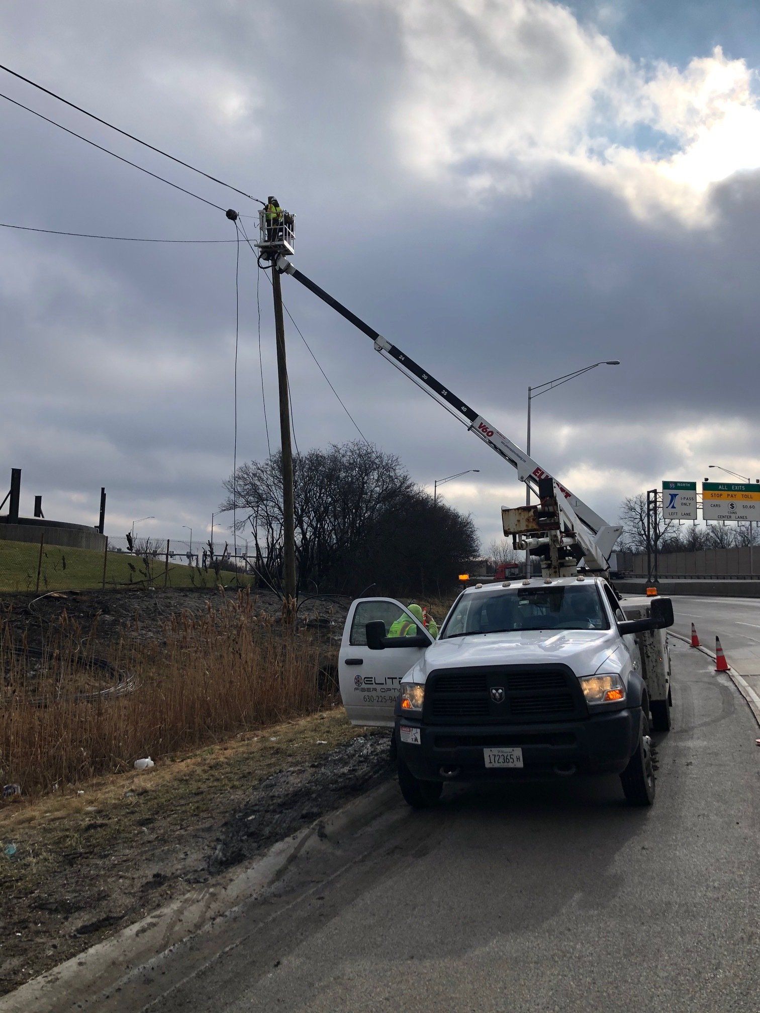 A white truck is parked on the side of the road next to a crane.