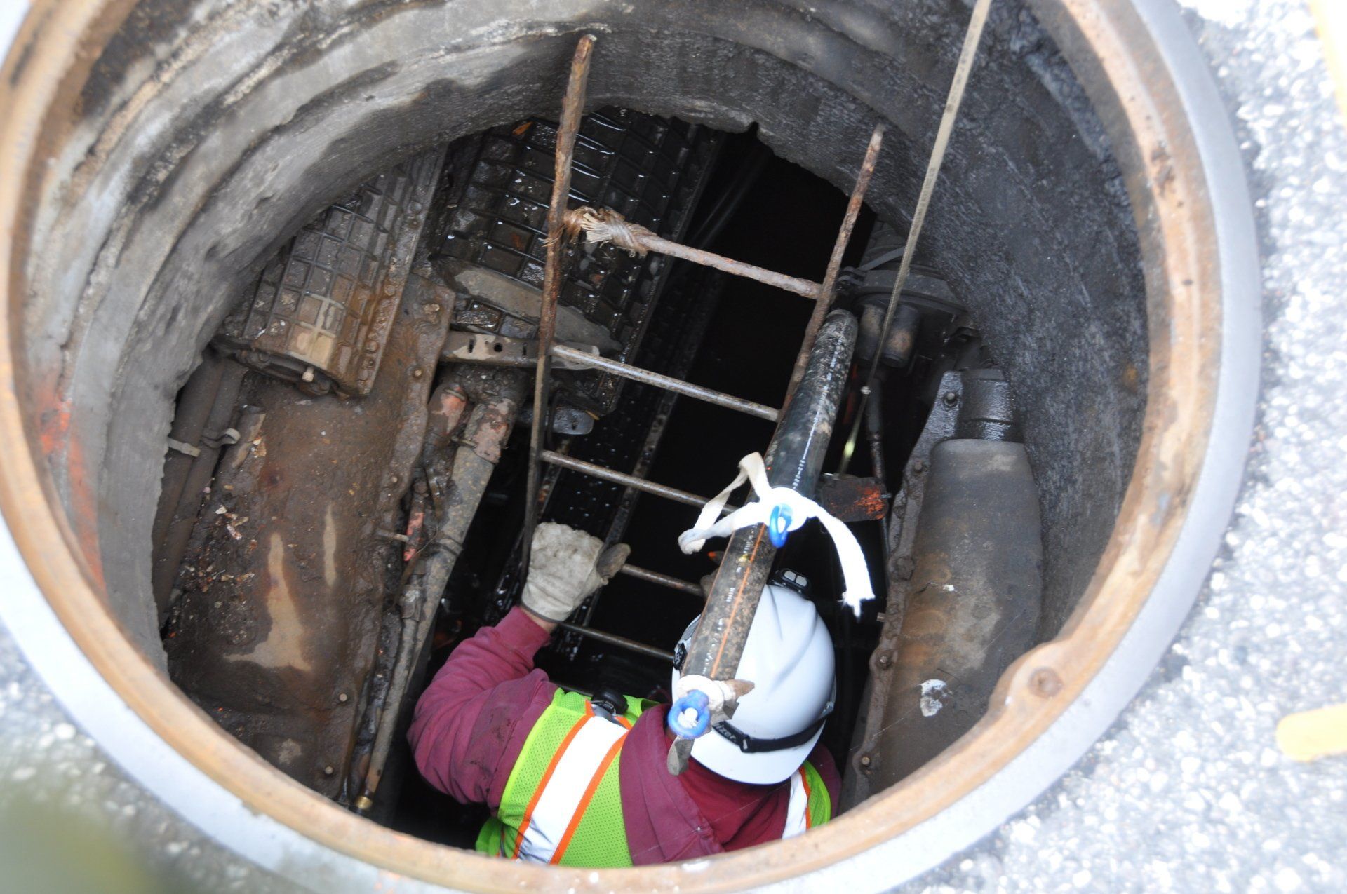 A man is using a ladder to get out of a manhole
