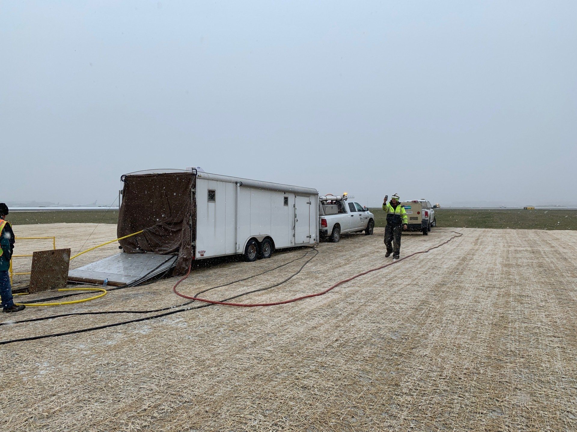 A trailer is being towed by a truck in a gravel field.