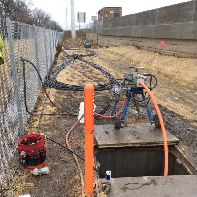 A hose is connected to an orange pole near a fence