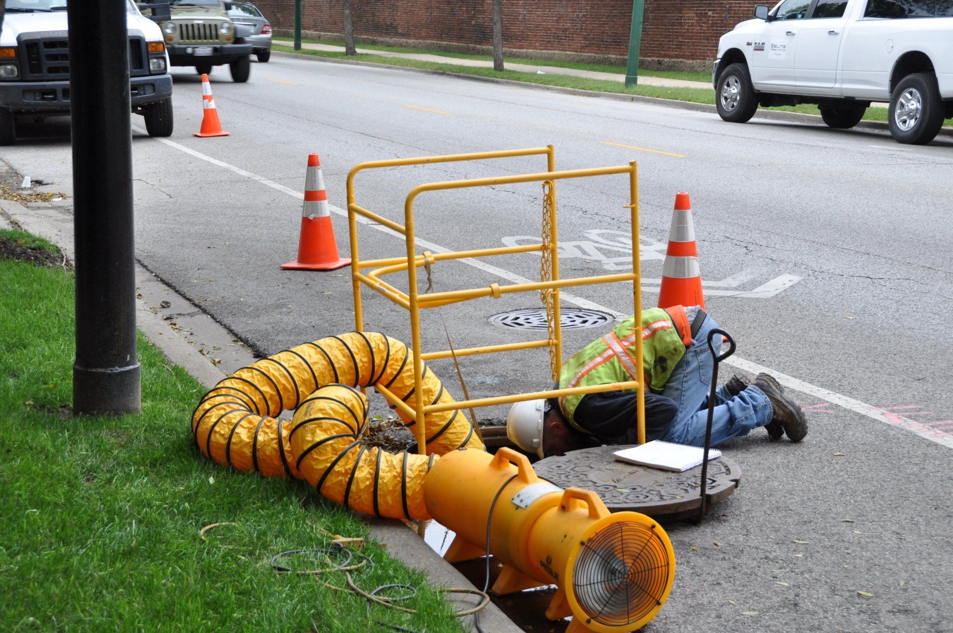 A man is laying on the side of the road next to a manhole cover