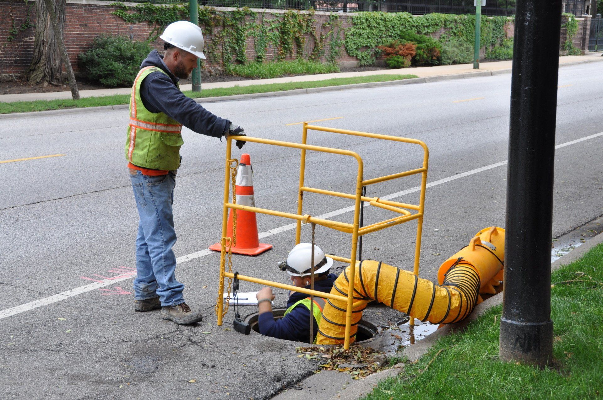 A man is laying in a hole on the side of the road