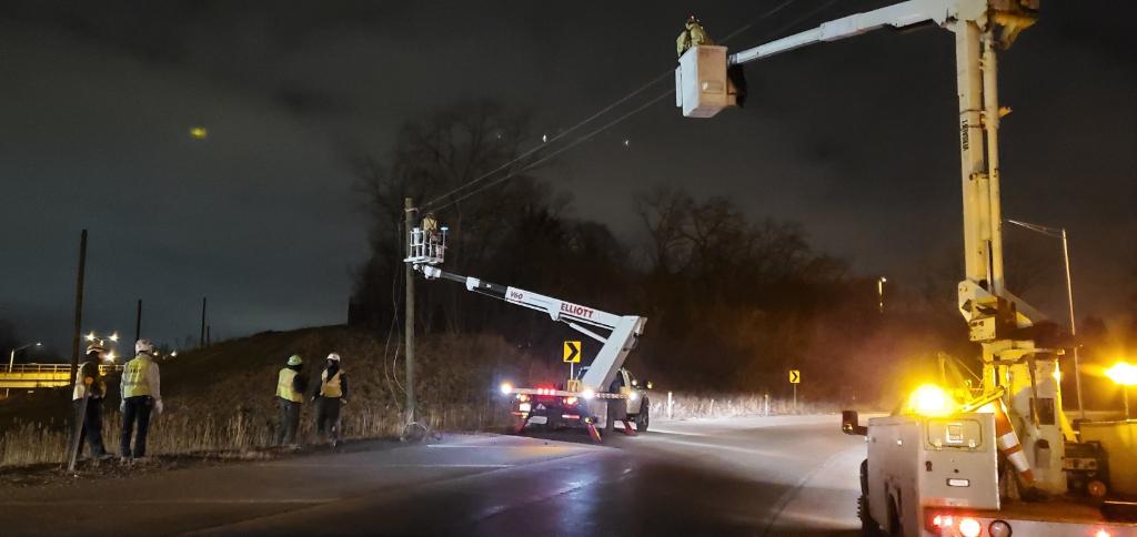 A group of people are working on a power line at night.
