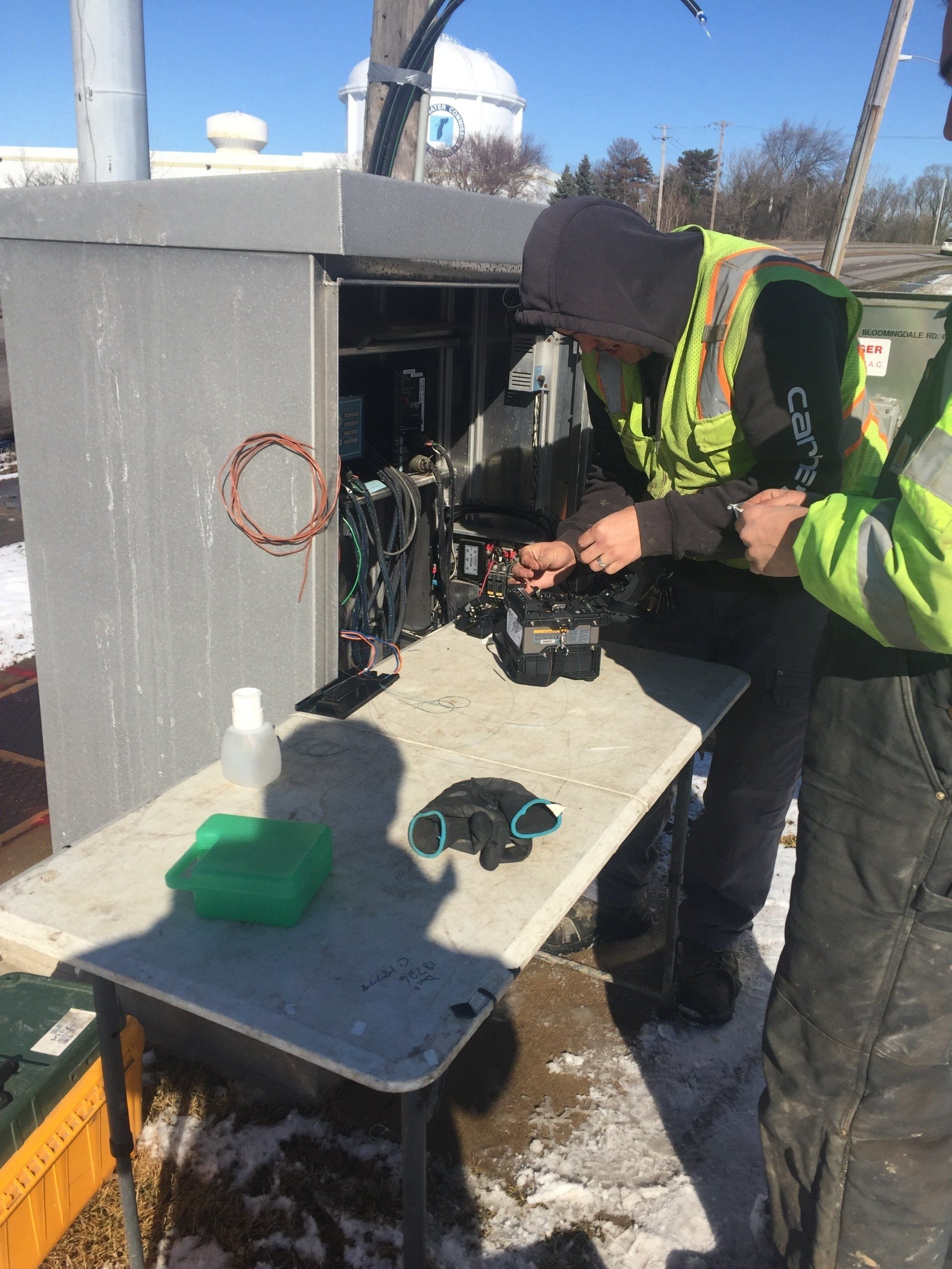 Two men are working on a box in the snow.