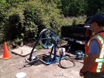 A man in an orange vest is standing next to a machine.