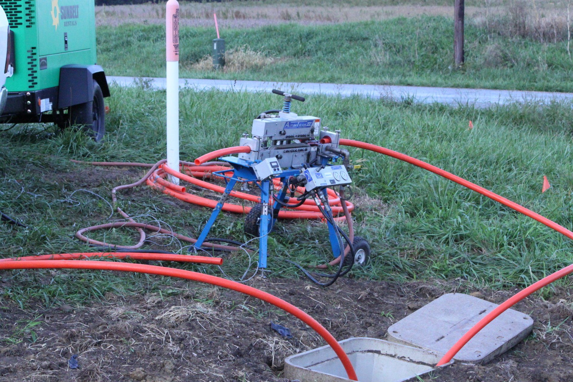A machine is sitting in the grass next to a hose.
