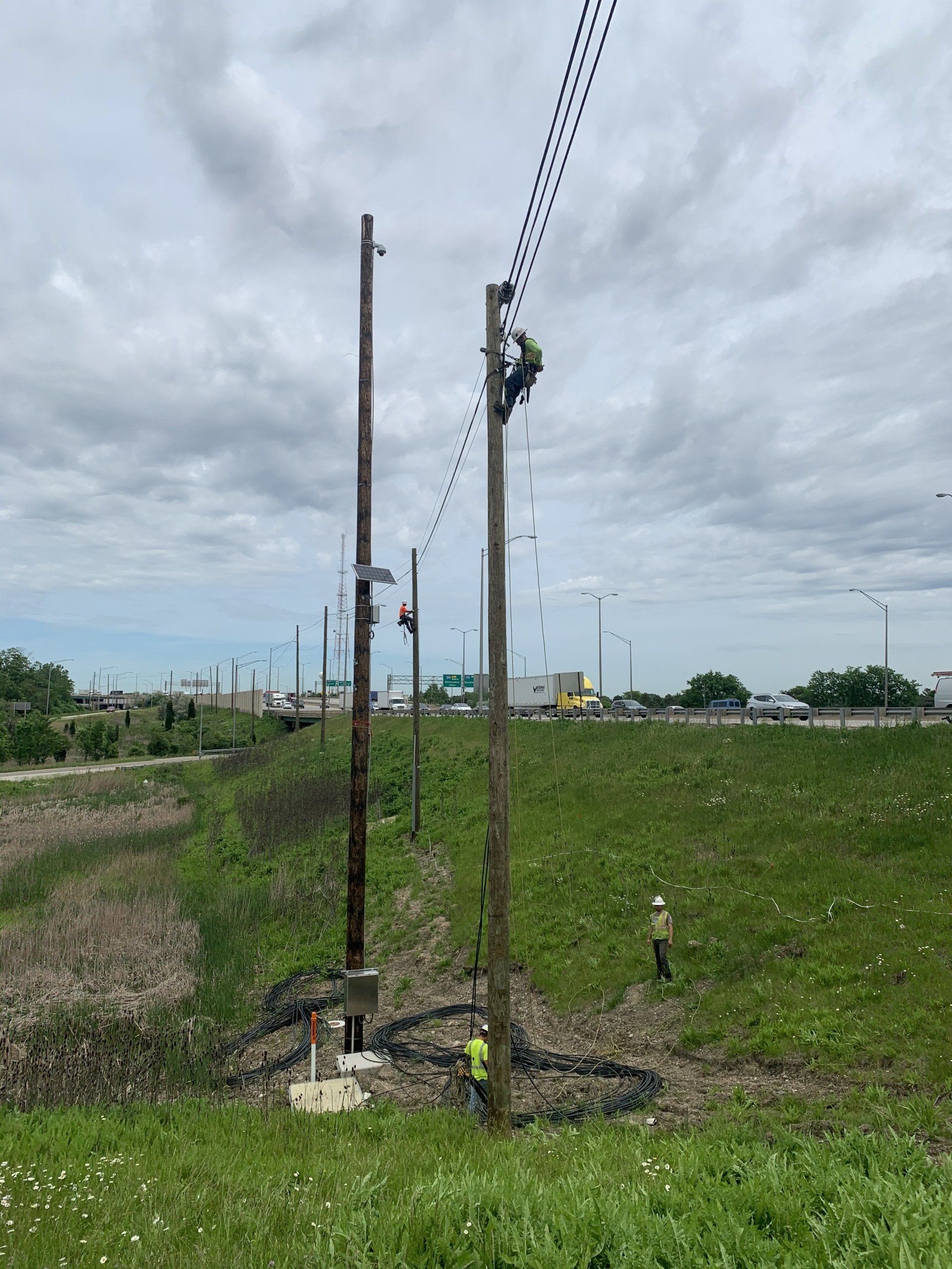 A man is climbing a power pole in a field.