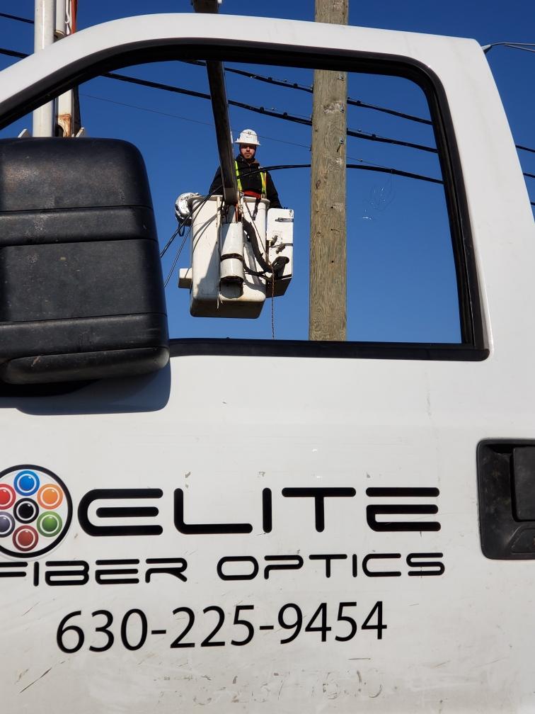 An elite fiber optics truck with a man in a bucket