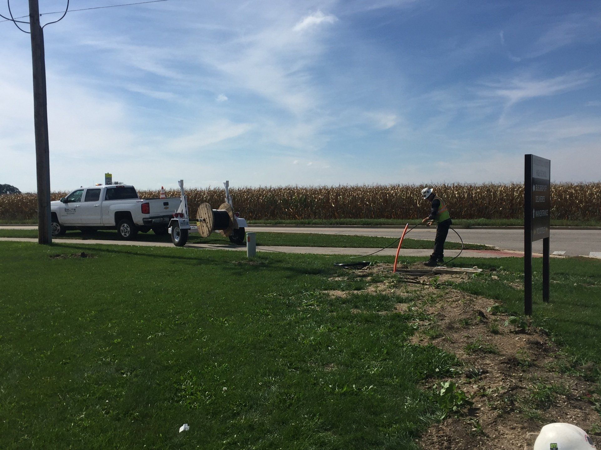 A white truck is parked on the side of the road next to a sign.